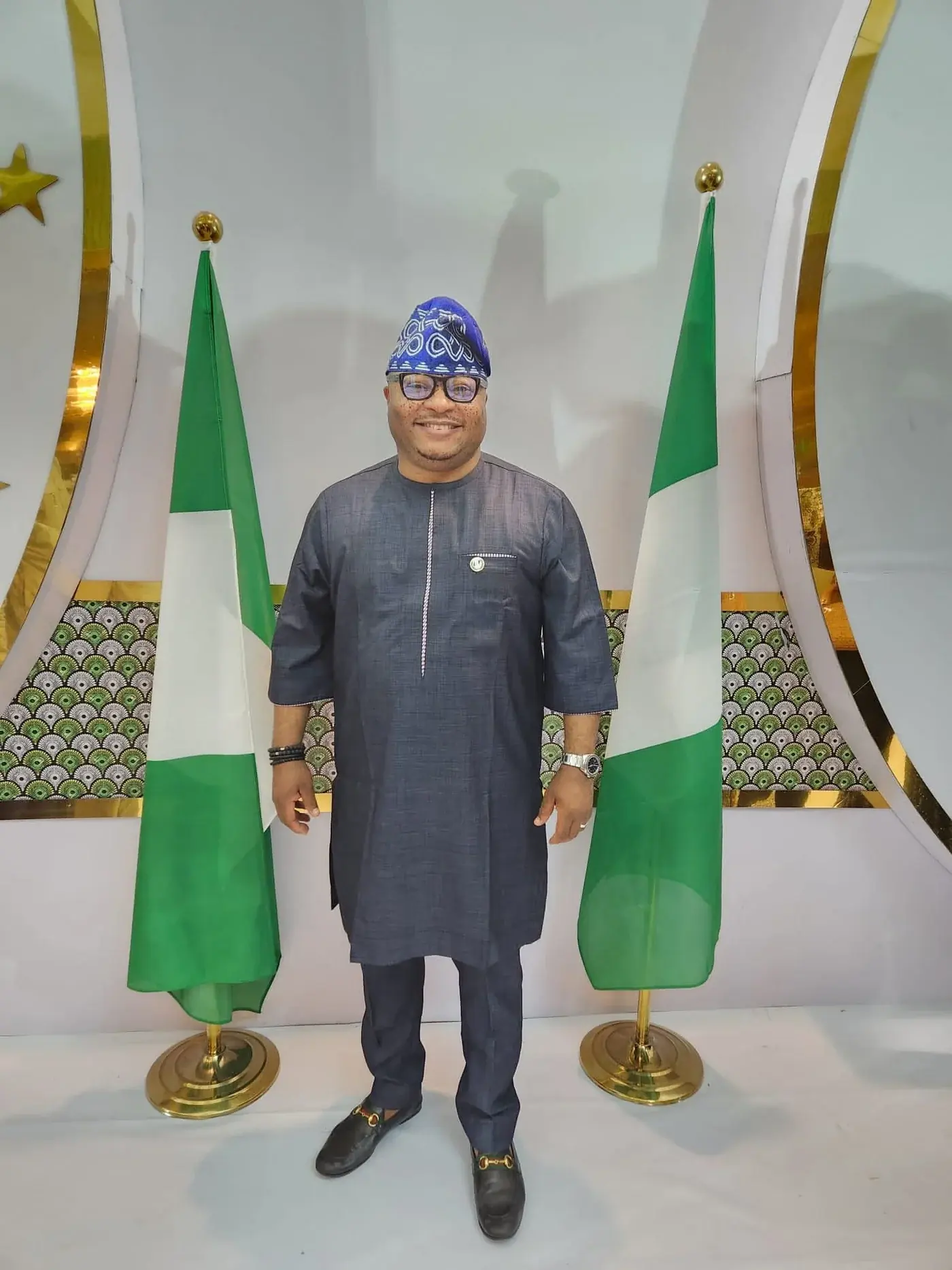 Dr. Rasheed Olayinka Alausa standing between Nigerian flags