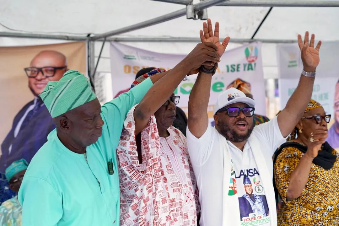 Dr. Rasheed Olayinka Alausa raising hands with supporters at a community event